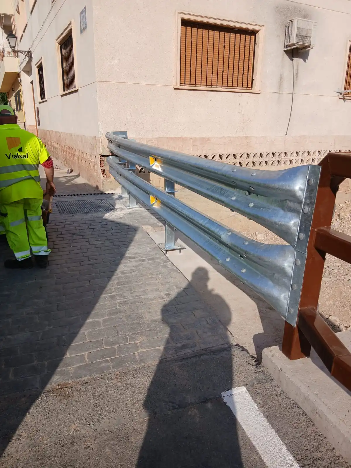 Instalación guardarraíl urbano operario obra señalización reflectante seguridad vial.