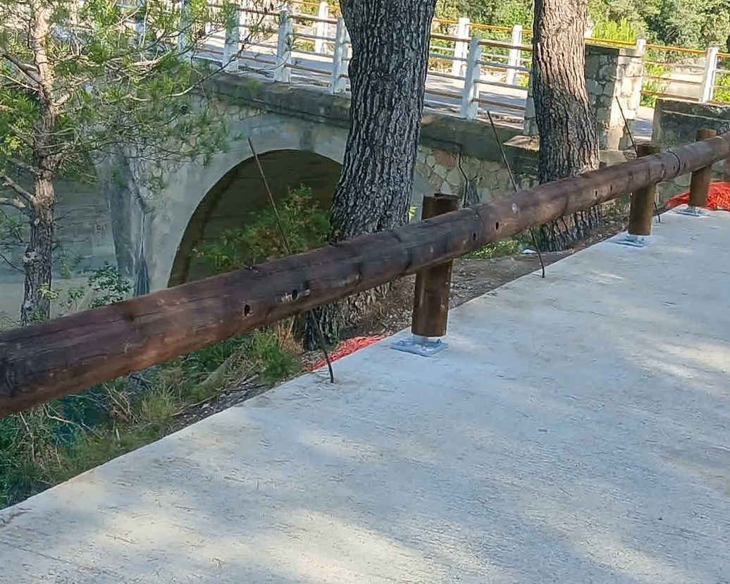 Barrera de seguridad vial de madera instalada junto a un puente
